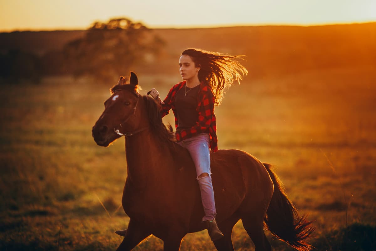 Person horseback riding in a field during summer camp
